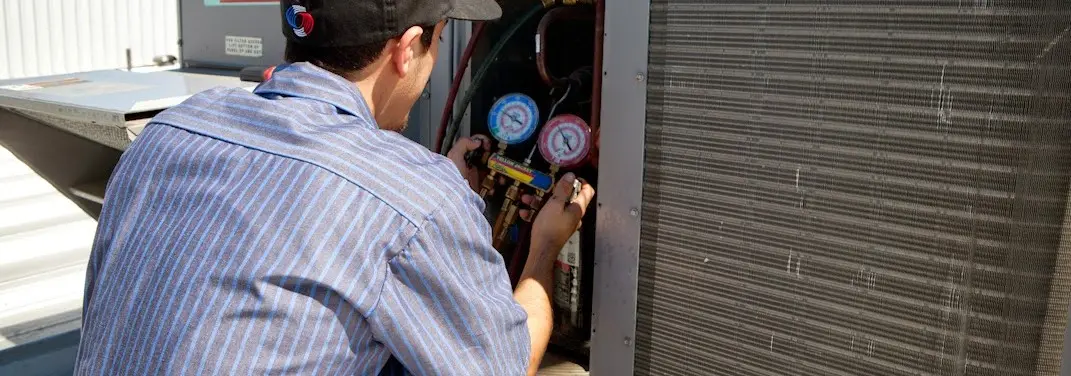 HVAC technician servicing a condenser unit in Bethalto