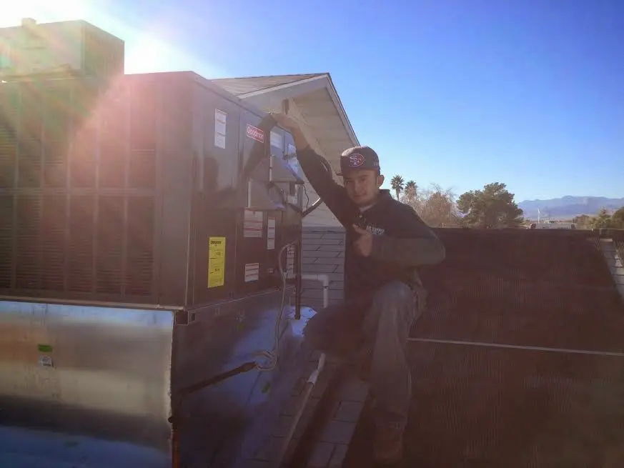 HVAC technician performing Heat Pump Repair on a rooftop unit in Bethalto